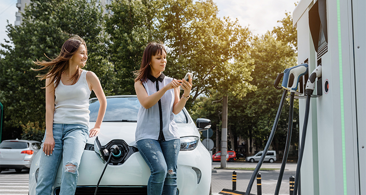 Two people using a phone to pay to use an EV charger.