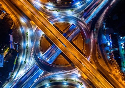 Aerial view of traffic in roundabout and highway at night.