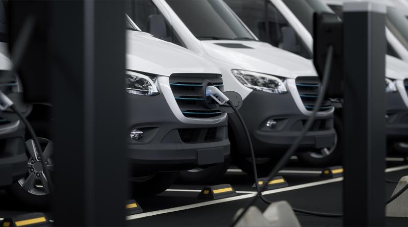 Image of a row of white electric trucks lined up at a charging station to support electric trucks article