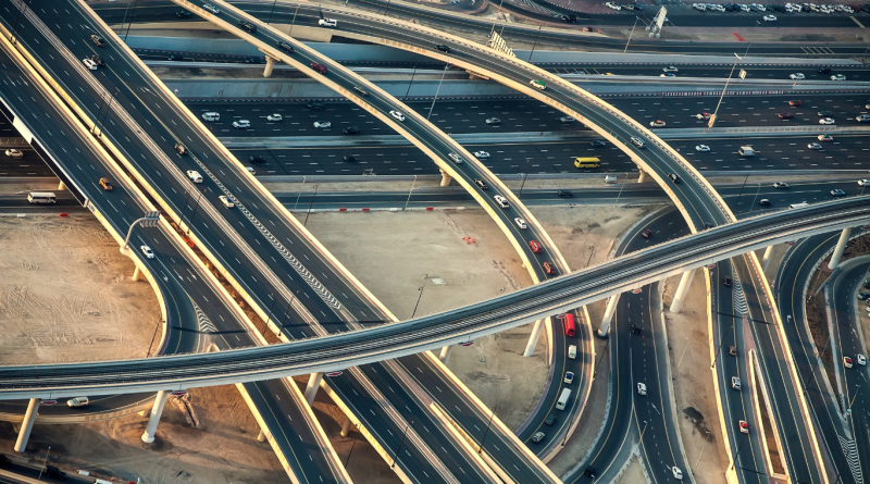 Aerial view of a modern highway interchange with cars and trucks, showcasing global transportation infrastructure.