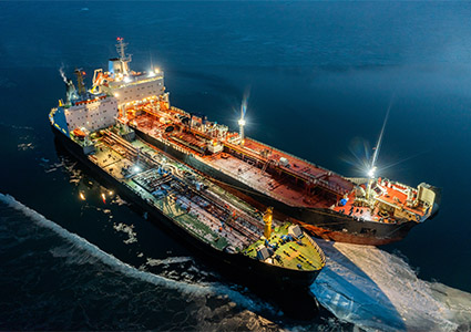 Two tankers at night, stand nearby in young ice