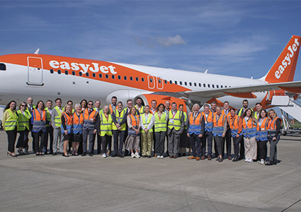 a large group of people posing for a photograph in front of an easyJet aircraft
