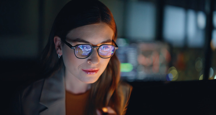 a focused professional working late, with data charts reflected in their glasses