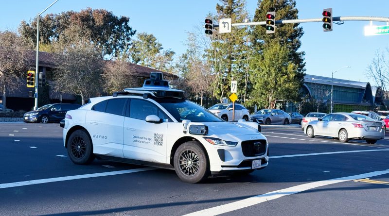 A Waymo autonomous vehicle driving in an urban street environment.