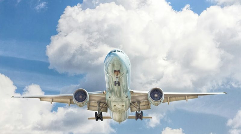 Commercial aircraft flying against a cloudy blue sky, representing aerospace systems and technology.