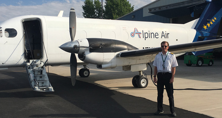 a pilot standing next to a twin-engine turboprop cargo aircraft
