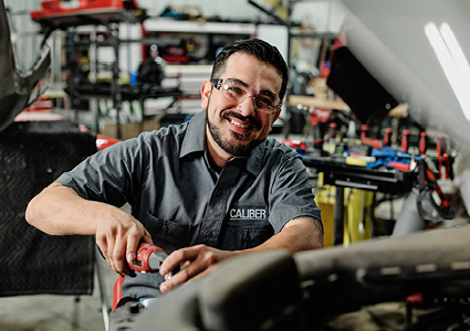 an automotive technician smiling while working in a repair shop