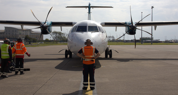 a white twin-engine turboprop passenger airplane parked on an airport tarmac
