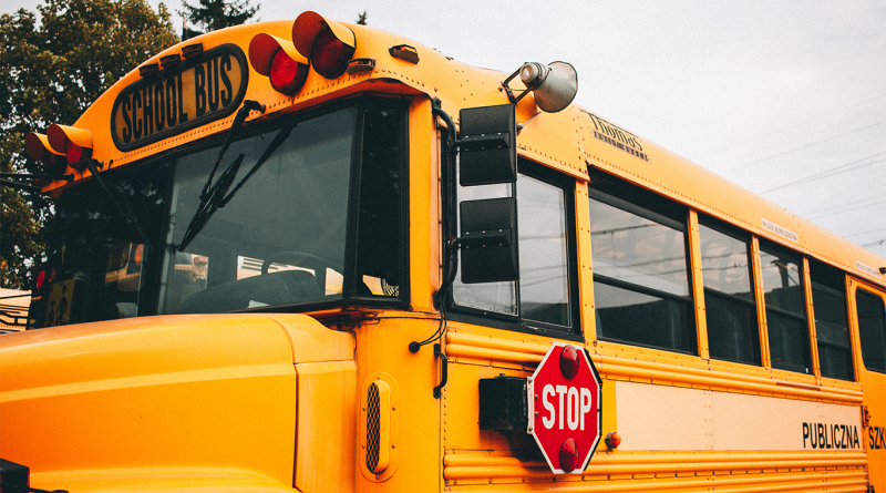 Close-up of a yellow school bus showing the front windshield, side windows and red stop sign.