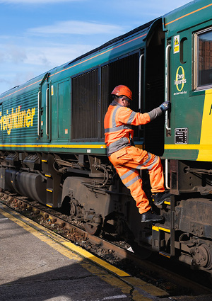 a railway worker climbing into the cab of a Freightliner diesel locomotive