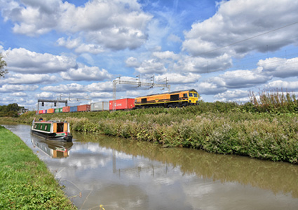 a yellow Freightliner intermodal freight train traveling alongside a narrow canal