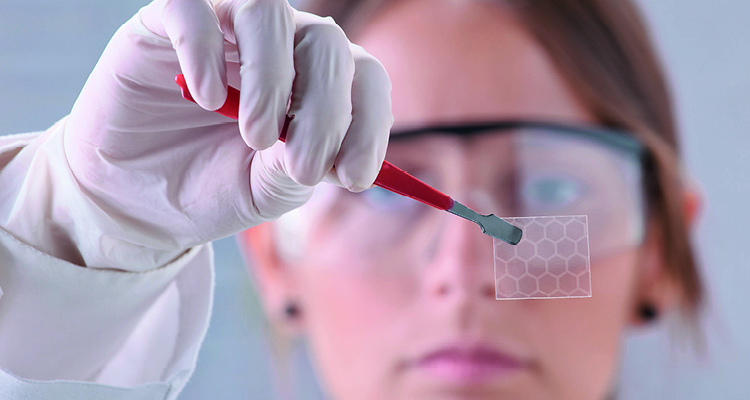 a scientist examining a sample of graphene, a single-layer carbon nanomaterial arranged in a hexagonal lattice pattern